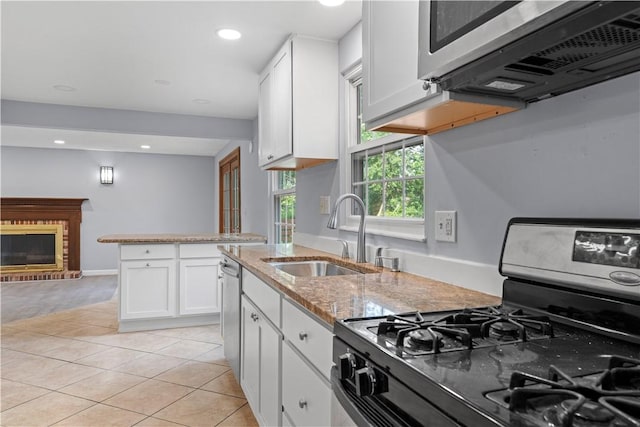 320 Penn Lear Ct, Monroeville, PA 15146 - kitchen with appliances with stainless steel finishes, white cabinetry, light tile patterned floors, light stone counters, and a brick fireplace
