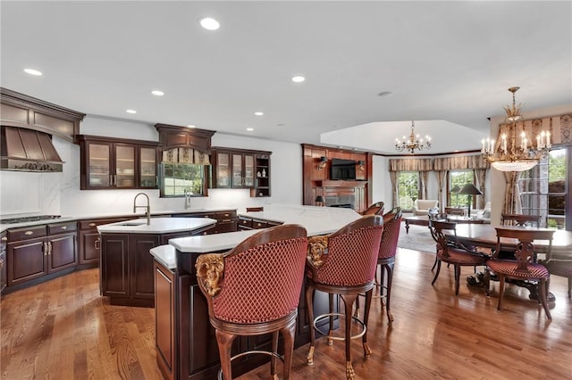 7023 Fair Oaks Dr, Export, PA 15632 - kitchen with a center island with sink, a chandelier, wood finished floors, dark brown cabinets, and stainless steel gas stovetop