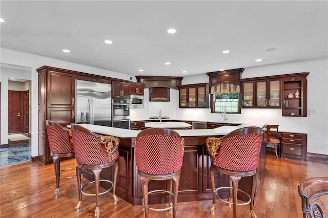 7023 Fair Oaks Dr, Export, PA 15632 - kitchen with built in appliances, a center island with sink, glass insert cabinets, dark wood-type flooring, and recessed lighting