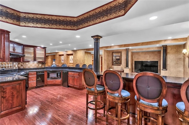 7023 Fair Oaks Dr, Export, PA 15632 - bar area with black microwave, ornate columns, under cabinet range hood, dark wood finished floors, and recessed lighting
