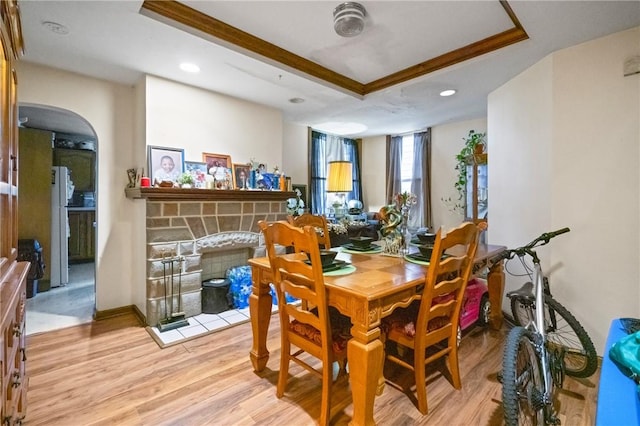 324 Linden Ave, Sharpsburg, PA 15215 - dining space featuring a fireplace, light wood-style flooring, a tray ceiling, recessed lighting, and arched walkways