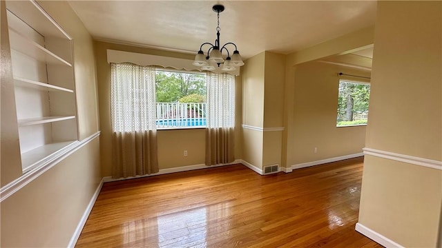 2231 Dellenbaugh Rd, Frazer, PA 15084 - empty room featuring a chandelier, healthy amount of natural light, wood finished floors, and built in shelves