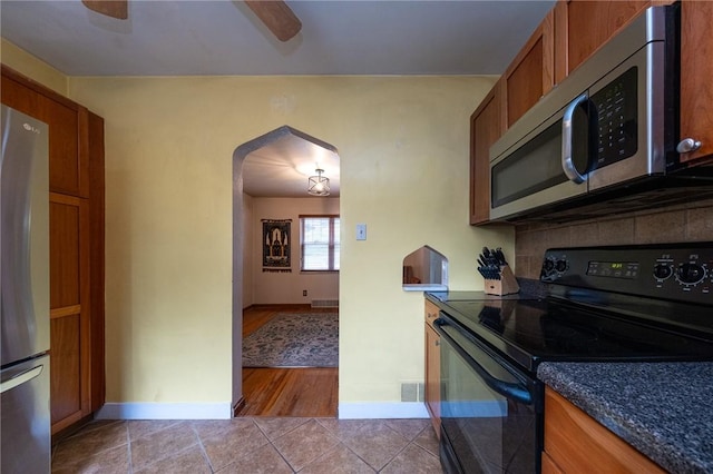 3037 Churchview, Baldwin Boro, PA 15227 - kitchen featuring appliances with stainless steel finishes, arched walkways, brown cabinetry, tile patterned floors, and dark countertops