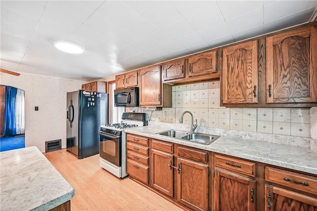 816 Wheatland Rd, Shenango Twp Mer, PA 16159 - kitchen featuring range with gas stovetop, black fridge, light wood-style flooring, light countertops, and tasteful backsplash