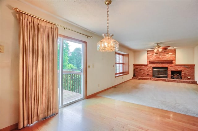 135 Jarod Dr, Moon/Crescent Twp, PA 15108 - unfurnished living room with a brick fireplace, wood finished floors, ceiling fan, and a chandelier