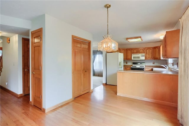 135 Jarod Dr, Moon/Crescent Twp, PA 15108 - kitchen with white appliances, light wood-style floors, a peninsula, hanging light fixtures, and light countertops