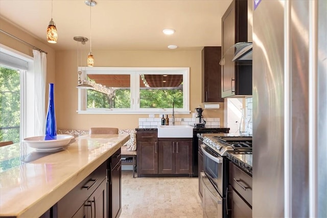 548 Penn St, Verona, PA 15147 - kitchen featuring appliances with stainless steel finishes, dark brown cabinets, decorative light fixtures, and light stone countertops