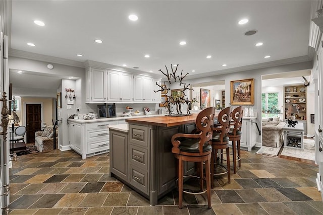 1909 Highgate Rd, Upper St Clair, PA 15241 - kitchen with ornamental molding, a kitchen island, white cabinetry, butcher block countertops, and a kitchen breakfast bar