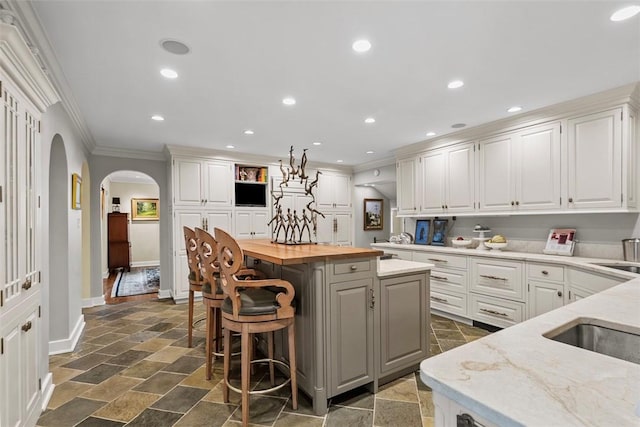 1909 Highgate Rd, Upper St Clair, PA 15241 - kitchen featuring ornamental molding, stone tile flooring, arched walkways, butcher block countertops, and a center island