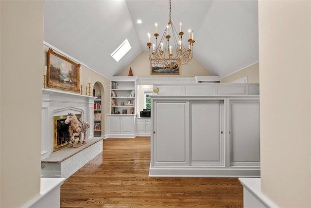 1909 Highgate Rd, Upper St Clair, PA 15241 - living room with built in features, a chandelier, light wood-type flooring, lofted ceiling, and a fireplace with raised hearth