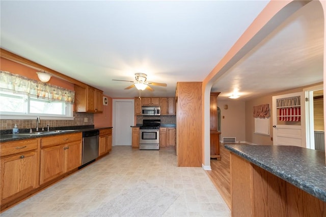 1539 Dime Rd, Parks Twp, PA 15690 - kitchen with appliances with stainless steel finishes, backsplash, brown cabinetry, dark countertops, and ceiling fan
