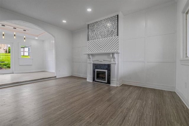 322 S Broadway St, Scottdale, PA 15683 - unfurnished living room featuring a decorative wall, arched walkways, wood finished floors, a tiled fireplace, and crown molding