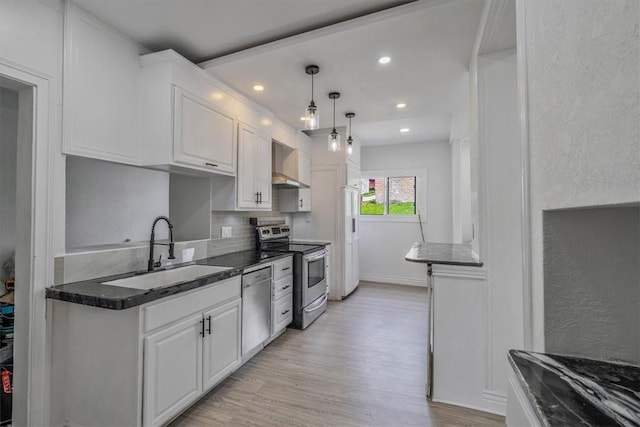 322 S Broadway St, Scottdale, PA 15683 - kitchen featuring appliances with stainless steel finishes, wall chimney exhaust hood, light wood-type flooring, white cabinets, and decorative backsplash