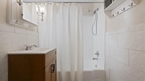 1657 Pembroke Dr, Pittsburgh, PA 15243 - bathroom featuring tile walls, vanity, and shower / tub combo with curtain
