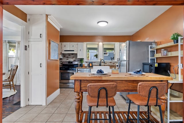 12091/2 Vance Ave, Coraopolis, PA 15108 - kitchen featuring stainless steel appliances, under cabinet range hood, light tile patterned floors, white cabinets, and backsplash