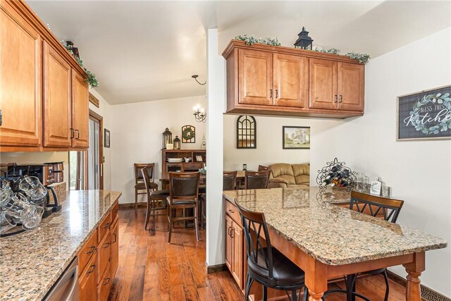 223 Horseshoe Dr, Adams Twp, PA 16046 - kitchen with a breakfast bar area, dark wood-type flooring, light stone countertops, and brown cabinetry