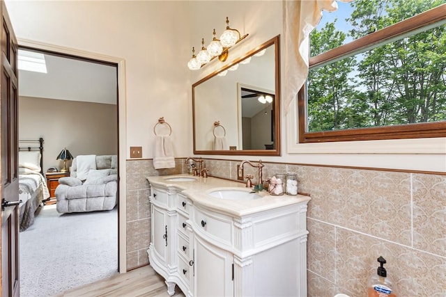 223 Horseshoe Dr, Adams Twp, PA 16046 - bathroom featuring tile walls, double vanity, wainscoting, ensuite bath, and wood finished floors