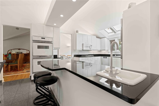 241 W Chapel Ridge Rd, Fox Chapel, PA 15238 - kitchen featuring white appliances, recessed lighting, dark countertops, white cabinetry, and a kitchen breakfast bar