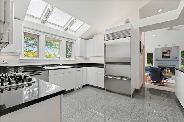 241 W Chapel Ridge Rd, Fox Chapel, PA 15238 - kitchen with stainless steel appliances, granite tiled floors, dark countertops, a lit fireplace, and white cabinetry