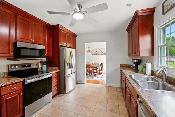 108 E Oakwood Way, Neshannock Twp, PA 16105 - kitchen with stainless steel appliances, reddish brown cabinets, ceiling fan, a chandelier, and light tile patterned floors
