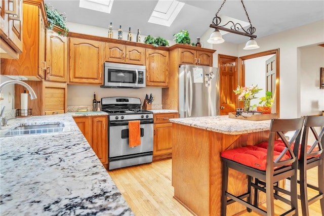 139 Village Dr, Cranberry Twp, PA 16066 - kitchen featuring appliances with stainless steel finishes, a skylight, light wood-style floors, a breakfast bar area, and vaulted ceiling