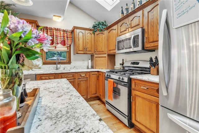 139 Village Dr, Cranberry Twp, PA 16066 - kitchen featuring stainless steel appliances, a skylight, vaulted ceiling, light wood finished floors, and light stone counters