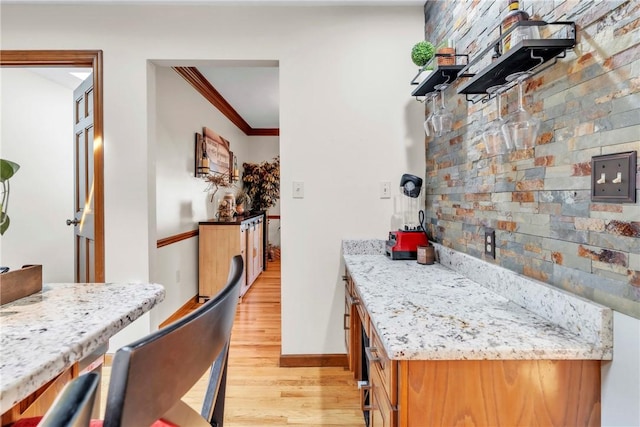 139 Village Dr, Cranberry Twp, PA 16066 - kitchen with light wood-style flooring, ornamental molding, brown cabinetry, and light stone countertops