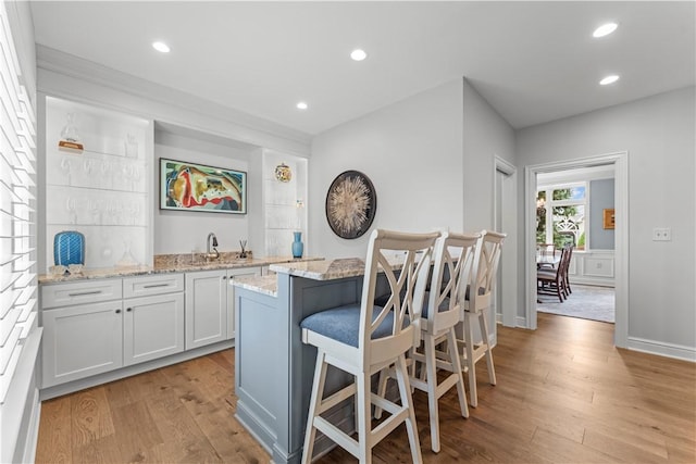 1055 Saint Mellion Dr, Collier Twp, PA 15142 - kitchen featuring light wood-style flooring, a breakfast bar, a kitchen island, light stone countertops, and white cabinetry