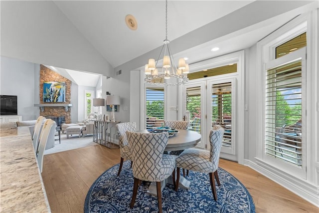 1055 Saint Mellion Dr, Collier Twp, PA 15142 - dining space with a chandelier, light wood-style flooring, a stone fireplace, high vaulted ceiling, and recessed lighting