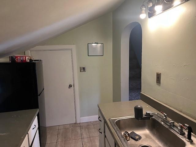 43 N 10th St, Sharpsville, PA 16150 - kitchen with vaulted ceiling, arched walkways, freestanding refrigerator, white cabinetry, and light tile patterned floors