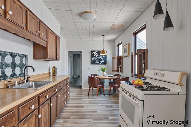 538 Maplewood Ave, Ambridge, PA 15003 - kitchen with white gas range, light wood finished floors, brown cabinets, pendant lighting, and light countertops