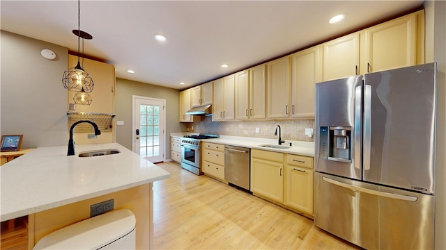 5445 Covode Pl, Squirrel Hill, PA 15217 - kitchen with appliances with stainless steel finishes, under cabinet range hood, light wood finished floors, backsplash, and hanging light fixtures