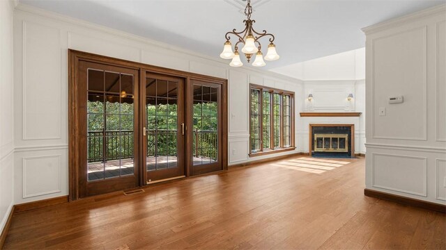 105 Bristol Sq, Ohara, PA 15238 - unfurnished living room featuring a decorative wall, a chandelier, wood finished floors, crown molding, and a fireplace with flush hearth