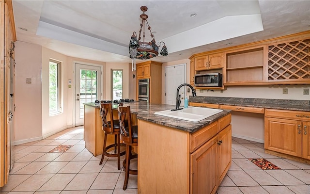 116 Parkfel Ave, Mccandless, PA 15237 - kitchen featuring stainless steel microwave, light tile patterned floors, a tray ceiling, an island with sink, and a kitchen breakfast bar