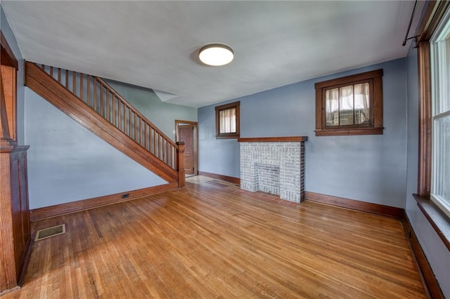 438 Miami St, East Mckeesport, PA 15035 - unfurnished living room with wood finished floors, stairway, and a brick fireplace