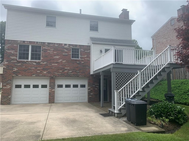 111 Brandywine Dr, Manor, PA 15642 - back of house featuring brick siding, a garage, driveway, a chimney, and a wooden deck