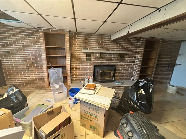 105 Fern Way, Glassport, PA 15045 - living room with a paneled ceiling, a wood stove, brick wall, and tile patterned flooring