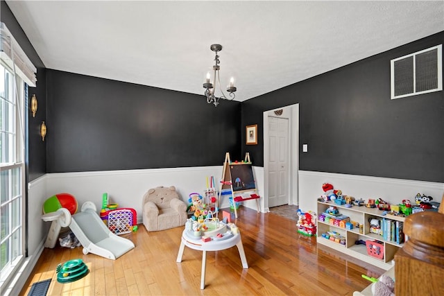 317 Shady Glen Dr, Moon/Crescent Twp, PA 15108 - playroom with wood finished floors, a chandelier, and a wainscoted wall