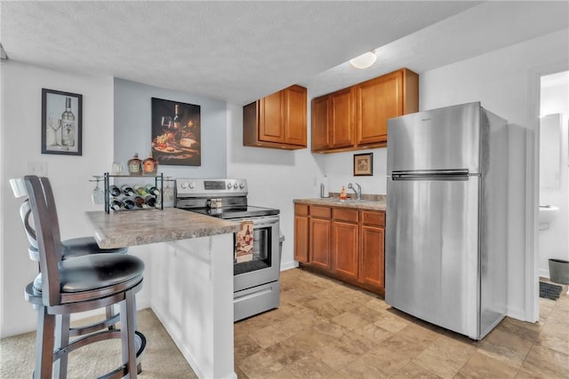 201 Millstream Ln, Zelienople Boro, PA 16063 - kitchen with stainless steel appliances, brown cabinets, light countertops, a textured ceiling, and a kitchen bar