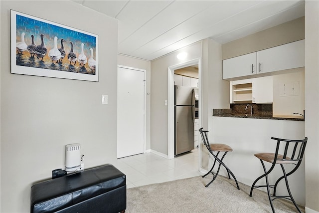 5 Bayard Rd Unit 113, Shadyside, PA 15213 - kitchen featuring freestanding refrigerator, white cabinets, light tile patterned floors, a breakfast bar area, and tasteful backsplash