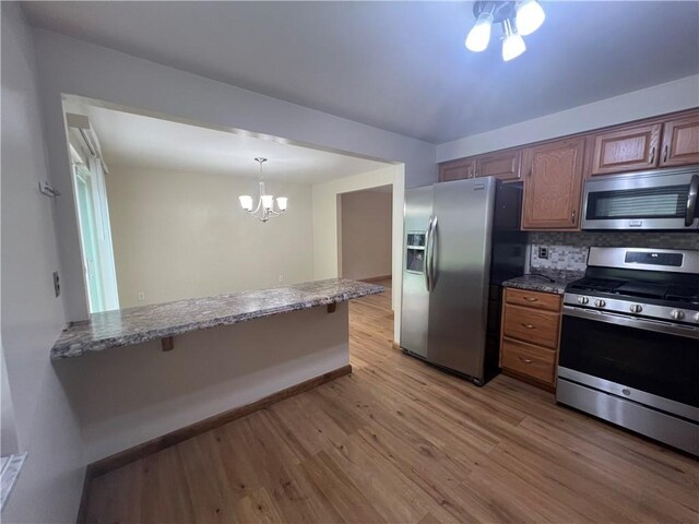 742 King St, Mckeesport, PA 15132 - kitchen with stainless steel appliances, light wood-style flooring, a chandelier, dark stone countertops, and tasteful backsplash