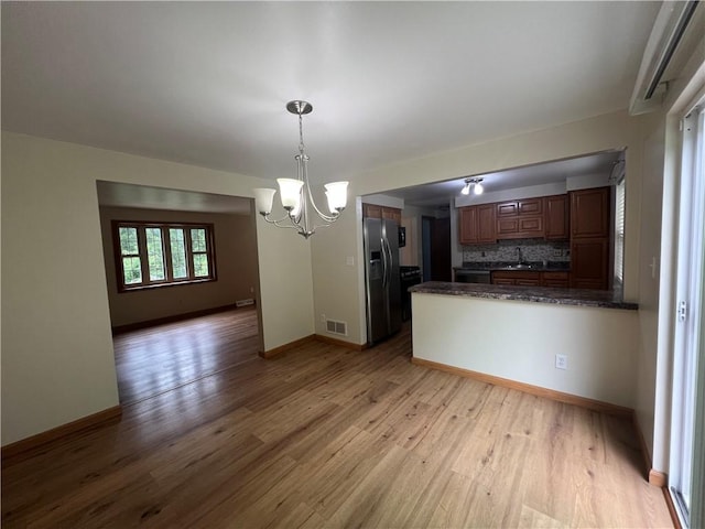 742 King St, Mckeesport, PA 15132 - kitchen with stainless steel fridge, dark countertops, a chandelier, and light wood-style floors