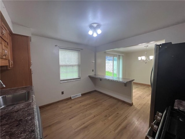 742 King St, Mckeesport, PA 15132 - kitchen with freestanding refrigerator, light wood finished floors, range, and brown cabinets