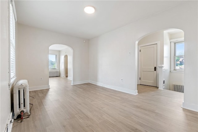 3937 Davis Ave, Munhall, PA 15120 - spare room featuring arched walkways, radiator, and light wood-style floors