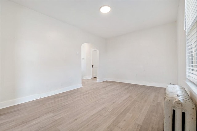 3937 Davis Ave, Munhall, PA 15120 - spare room featuring radiator heating unit, light wood finished floors, and arched walkways