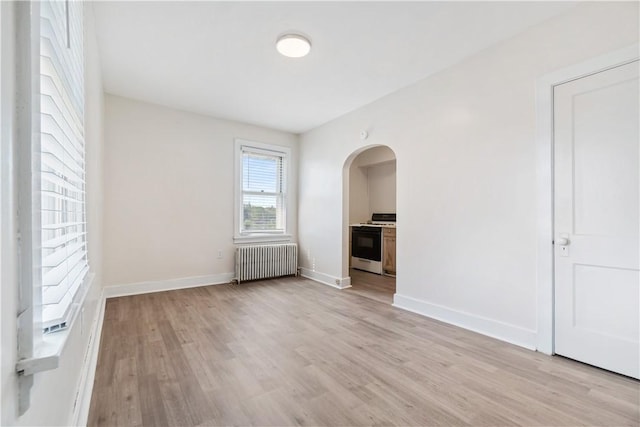 3937 Davis Ave, Munhall, PA 15120 - unfurnished living room with radiator heating unit, arched walkways, and light wood finished floors