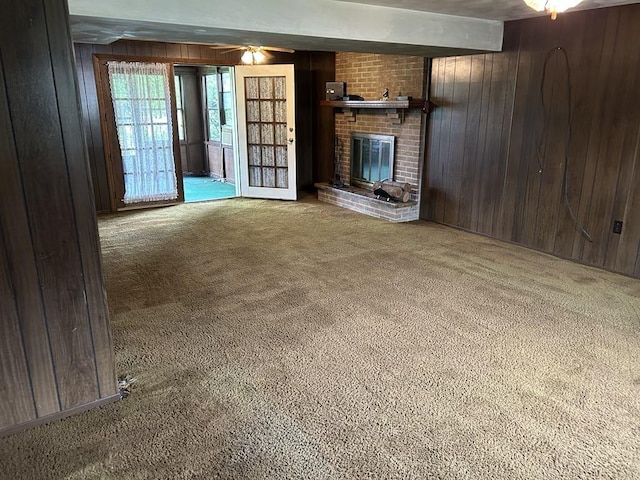 307 Debora Dr, Latrobe, PA 15650 - unfurnished living room featuring wooden walls, carpet flooring, ceiling fan, and a brick fireplace