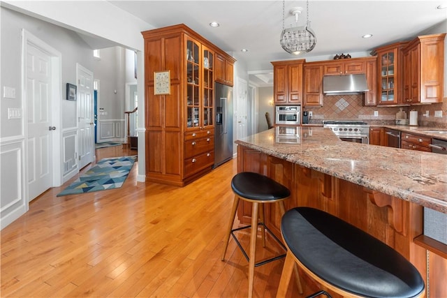 1002 Sunset Way, Menallen Twp, PA 15401 - kitchen with under cabinet range hood, high end appliances, brown cabinetry, backsplash, and recessed lighting