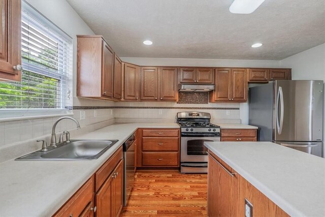 520 Panorama Dr, Cecil, PA 15317 - kitchen with appliances with stainless steel finishes, light wood-style flooring, under cabinet range hood, light countertops, and decorative backsplash