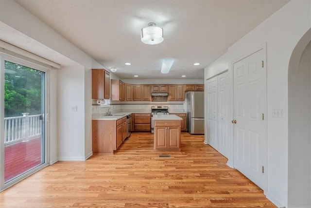 520 Panorama Dr, Cecil, PA 15317 - kitchen with stainless steel appliances, light countertops, arched walkways, light wood-type flooring, and a center island